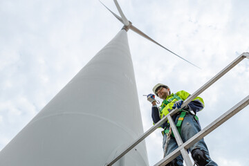 Wind turbine technicians holding walkie talkie standing under at turbine station. man engineer...