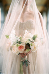 Bouquet of flowers in the hands of a bride in a veil. Close-up