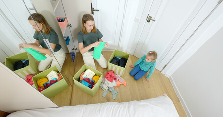 Mom and daughter sort clothes, put things in the closet