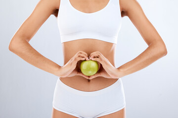 Digestion, apple and woman stomach with hands in heart shape for nutrition, detox diet and studio...