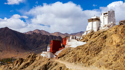 Panorama winter landscape of Leh palace with five color prayer flags blowing in the wind, Leh palace in the background.Tsemo Namgyal monastery in Ladakh,India.Blue sky with clouds.Himalayan range. - obrazy, fototapety, plakaty