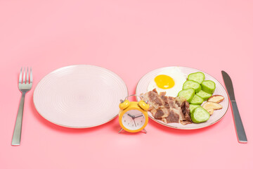 Plate with food and empty plate on pink background, intermittent fasting concept.