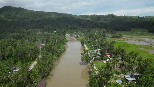 Polluted river water in poor area of provincial city in Taiwan. Acute environmental problem associated with water and environmental pollution. River with green trees, houses and shacks on its banks.