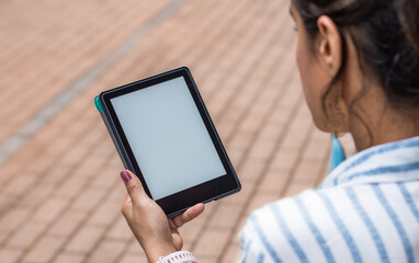 Over The Shoulder View of A Young Woman Using Digital Tablet With Blank White Screen Mock Up