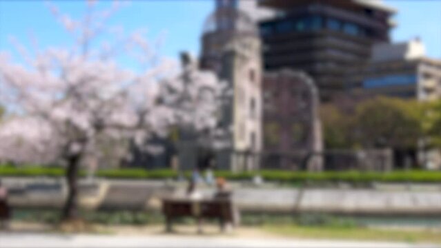 ぼかし背景素材: 桜咲く春の広島平和記念公園でベンチに座り花見を楽しむ人々 4K  2022年4月1日