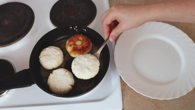 Women's hands put cottage cheese pies on a hot pan. Cheesecakes are fried in a pan. The process of preparing delicious homemade food. cheesecakes or cheesecakes. close-up. Cottage cheese balls, health