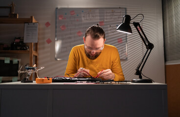 Handsome bearded engineer repairing laptop computer. Repairman working in technical support fixing...