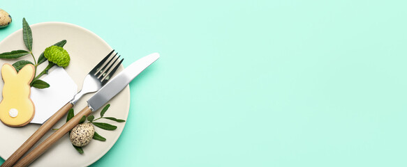 Stylish table setting with Easter cookie and eggs on turquoise background with space for text