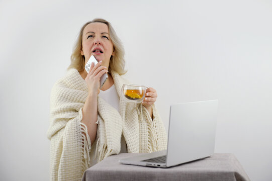 Cold Flu Look For A Way Out Treatment Options Think Middle-aged Adult Woman Is Looking For How To Cure Illness Recipes Folk Remedies Near A Laptop With A Phone In Her Hands Plaid On Her Shoulders