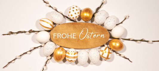 Frohe Ostern Feier Feiertage Hintergrund mit deutschem Text - Rahmen aus Holzschild, goldenen Ostereiern und Palmkätzchen isoliert auf weisser Textur, Draufsicht