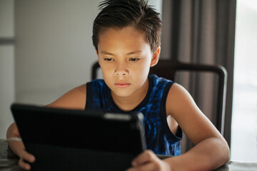 Young boy playing games online, concentrating looking on screen