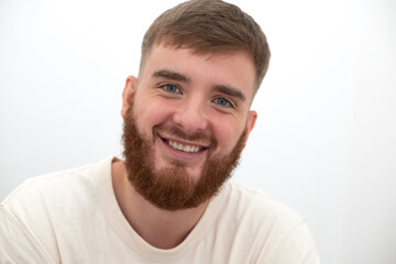 Obraz premium Portrait of bearded happy young handsome man with beard is smiling on white background and looking at camera