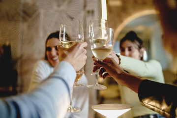 Multiethnic group of Friends toasting with white wine in a restaurant