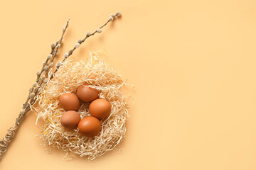 Nest with Easter eggs and willow branches on color background