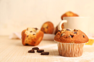 Delicious muffin with chocolate on beige wooden table