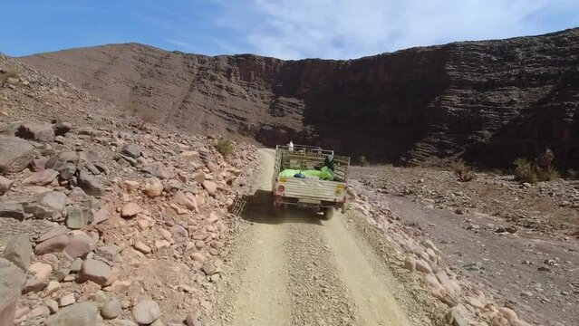 Point of view of a motorcycle driver behind an old pickup in desertic mountain trail