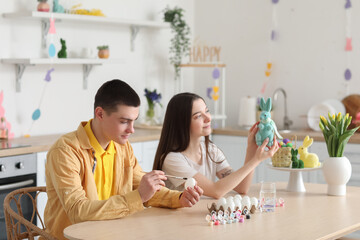 Young woman with Easter rabbit and her boyfriend in kitchen