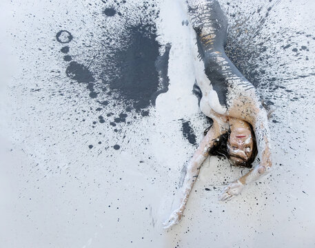 sexy nude woman in black and white color painted, lying decorative on the white, black, gray Studio floor, rolls to the side and leaves an imprint of her body