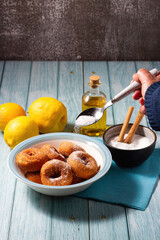 Woman's hand sprinkling sugar on fried homemade doughnuts. Traditional Spanish pastries.