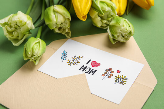 Envelope, card with text I LOVE MOM and tulips on green background, closeup