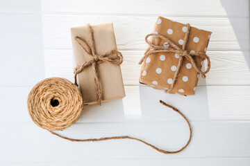 Fototapeta na wymiar Eco gift wrapping. Brown gift boxes tied with a rope on white wooden background. Flat lay