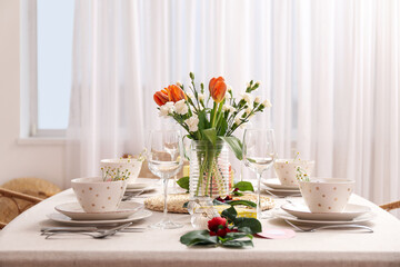 Fototapeta na wymiar Table setting for International Women's Day celebration and vase with flowers in dining room