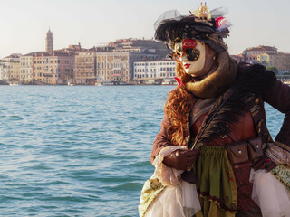 Carnival time and masked lady with hat gather in costume in Piazza San Marco Venezia at sunset. - Powered by Adobe