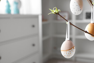 Tree branches with Easter eggs in living room, closeup