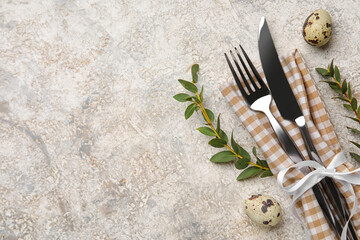 Cutlery with napkin, Easter eggs and plant branches on grunge background