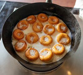 Donuts are fried in a frying pan in oil.