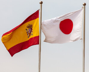 Flags of Japan and Spain against the sky.