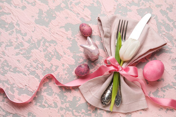 Table serving with Easter eggs, bunny and tulip flower on pink grunge background