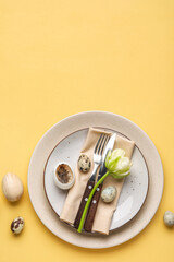 Fototapeta na wymiar Table serving with Easter eggs and tulip flower on yellow background
