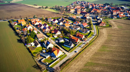 Aerial view from the edge of a small German village beetween fields and meadows with family houses...