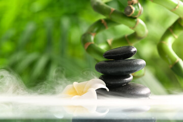 Stack of spa stones and flower in water outdoors