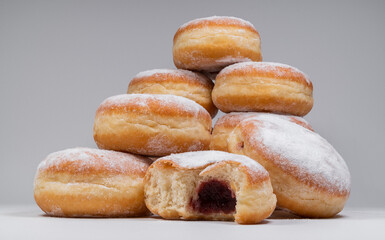 Polish pączki deep-fried doughnuts. Celebrating Fat Thursday, Tłusty czwartek feast, traditional day in Poland. Pączek food, powdered sugar topped and filled with rose hip jam.