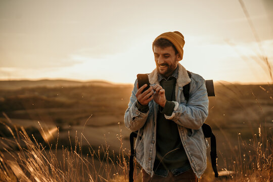 Spontaneous photo of an adventure man holding a phone and using maps, a hiker, nature lover enjoying the view where he is walking while enjoying the fresh air on a beautiful sunny autumn day.