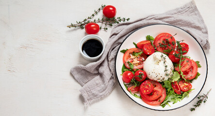 Delicious caprese salad with tomatoes and mozzarella cheese with fresh leaves. Italian food.