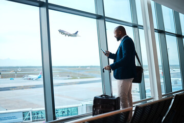 Black man with phone, airport window and plane taking off, checking flight schedule terminal for...