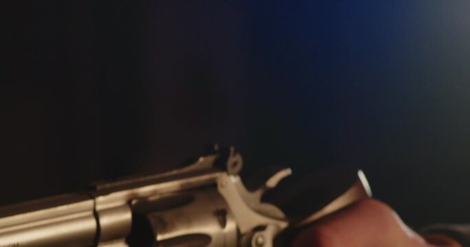 Close up of Finger pulling trigger of revolver and shooting. Smoke passes in front of the camera
