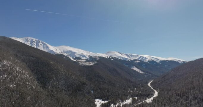 Aerial shot of mountains outside of winter park with plane flying in distance