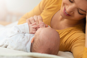 Mom talks and laughs with her newborn son at home bedroom croped