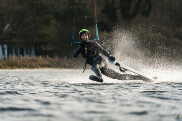 Kitesurfer sliding over the water surface with one foot out on a sunny day
