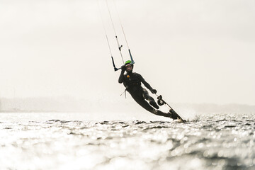 Kitesurfer sliding over the water surface on a sunny day