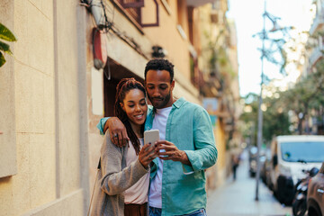 African American couple using mobile phone outside.