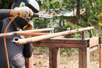 A worker uses tools to weld steel.