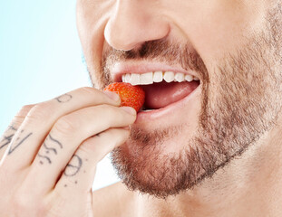 Health, eating and strawberry with mouth of man for diet, detox and nutrition product. Wellness, smile and teeth with model and biting fruit closeup for vitamin c, glow and fiber in blue background