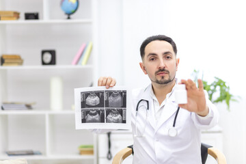 Photo of doctor wearing lab coat showing an ultrasound result to his patient.