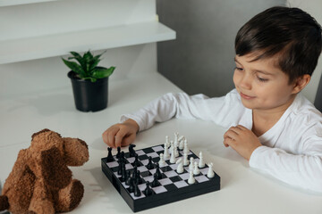 cute boy is playing chess with his toy	