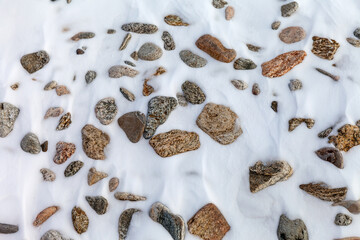 Flat lay of snowy beach in cold winter day. Natural texture with snow-covered stone seaside. Winter background, top view, mock up